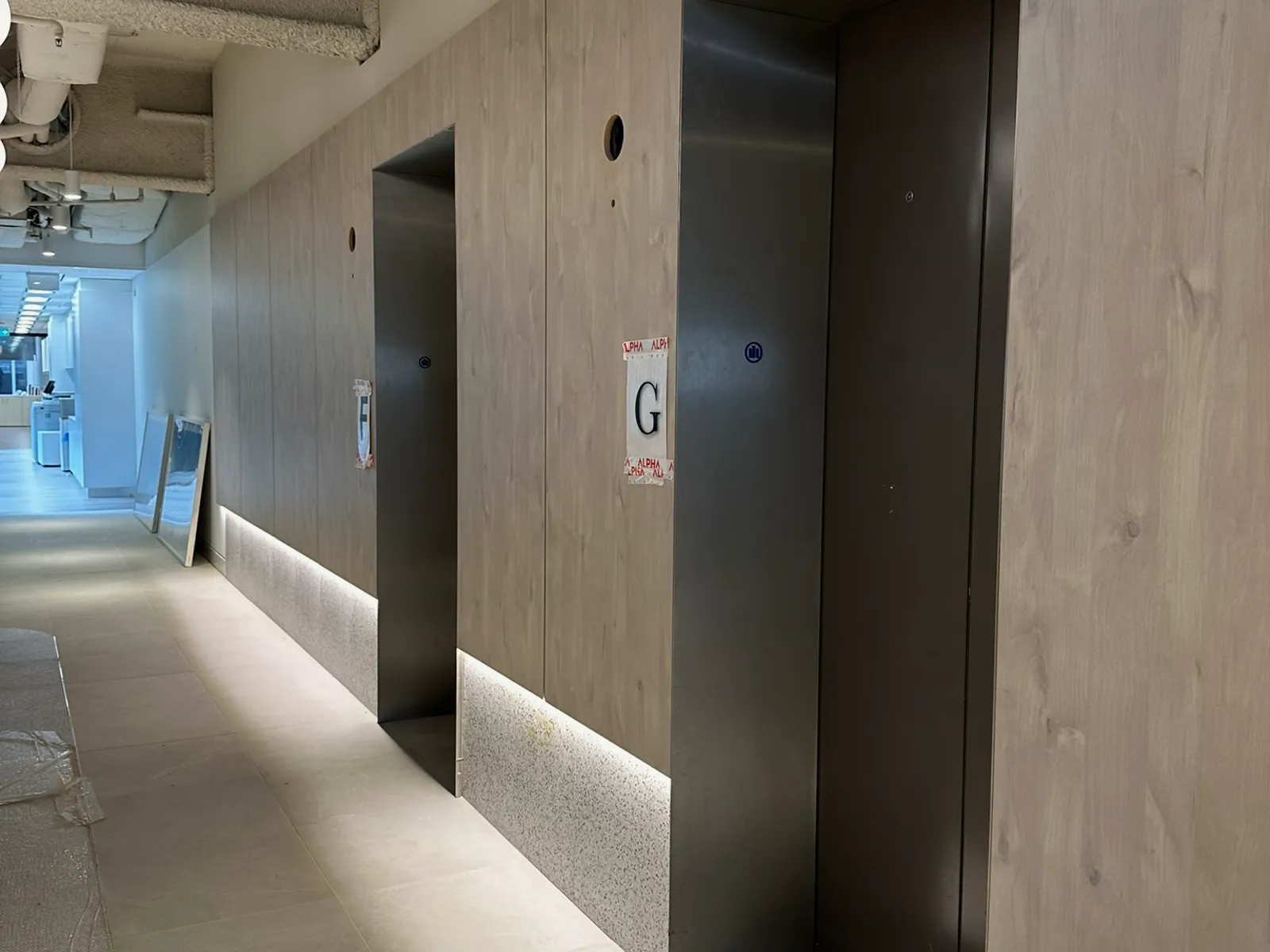 Lift lobby corridor with timber-look wall panelling and lift doors F and G, Sydney CBD commercial building
