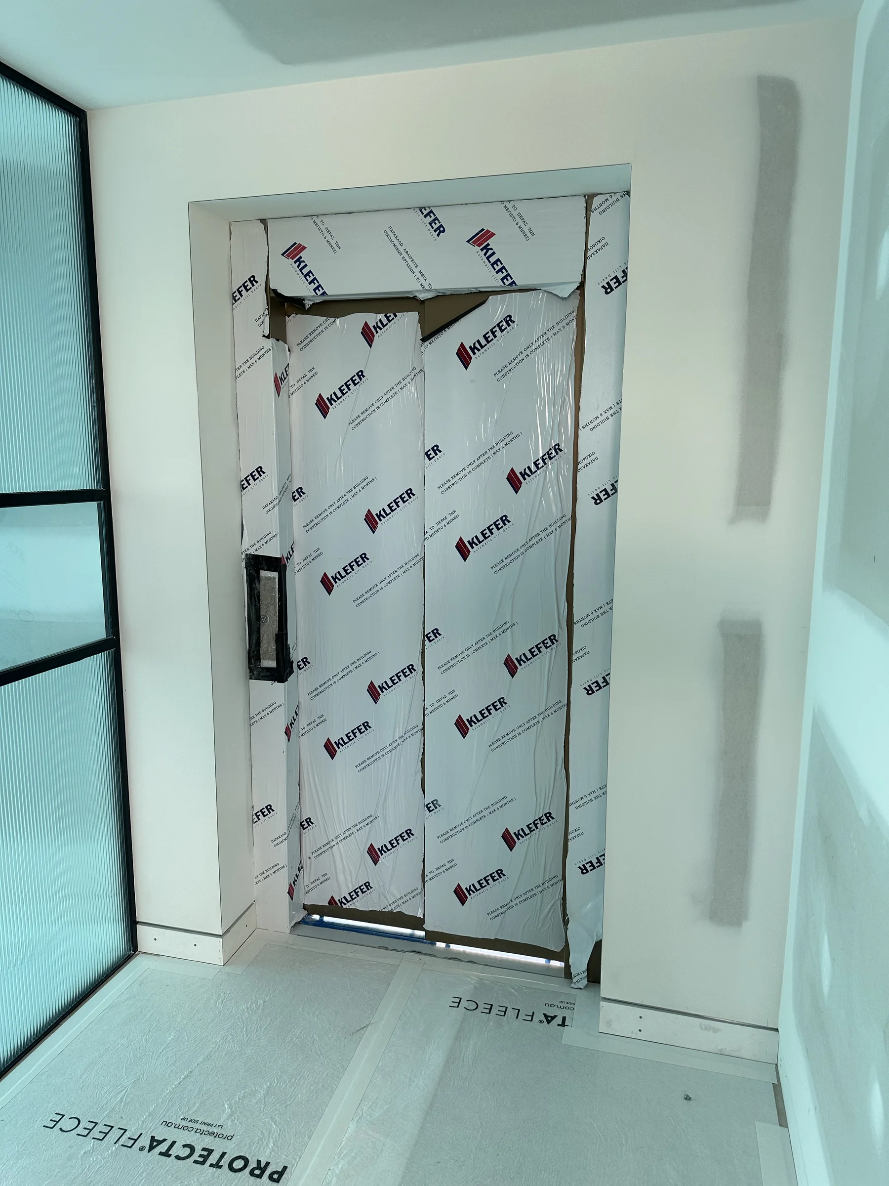 Lift mid-installation, protected under film, during a Potts Point commercial fitout