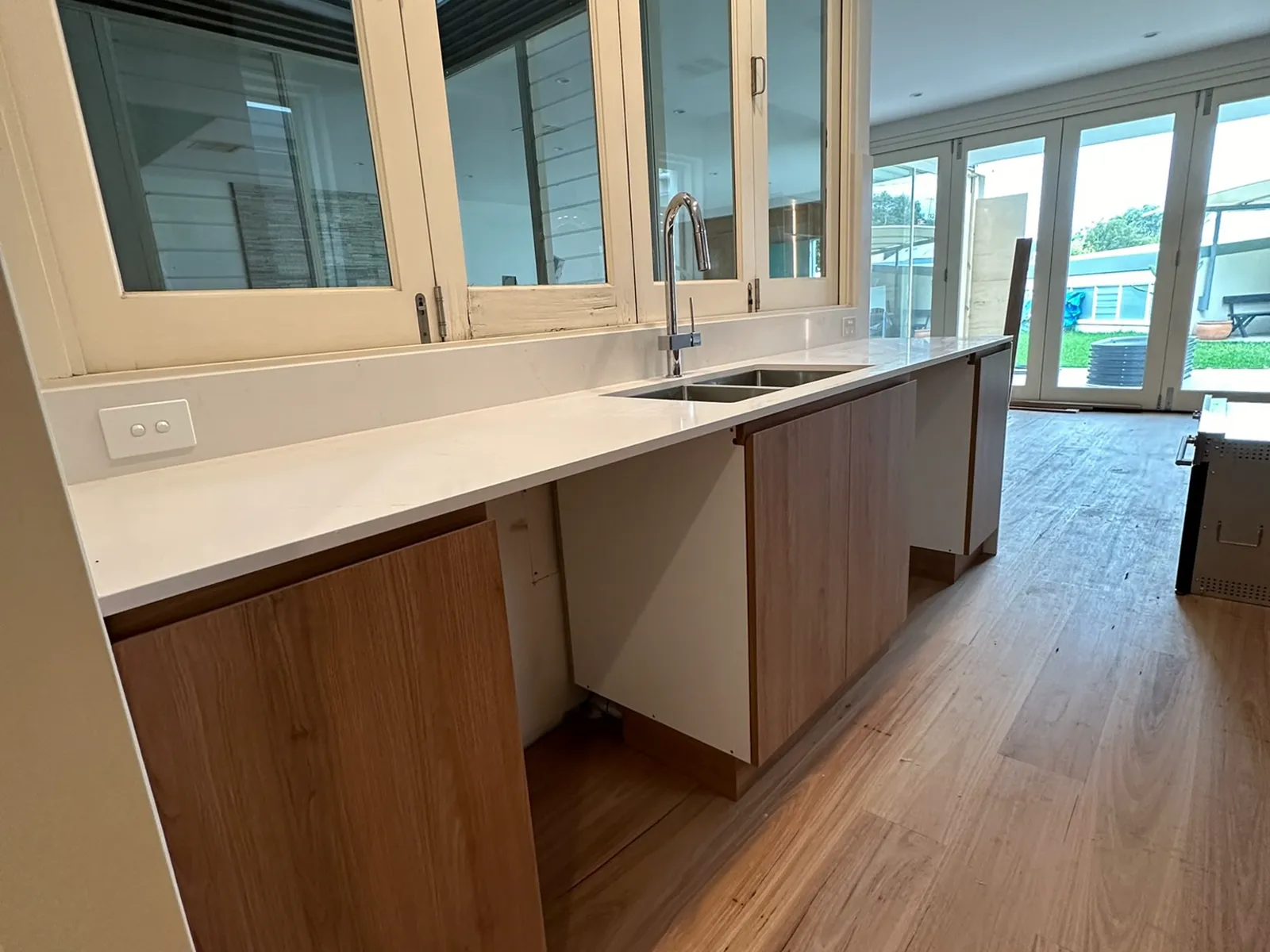 Kitchen benchtop, undermount sink and tapware installed beneath the original timber-framed windows, Bondi Junction